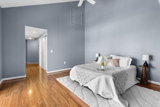 bedroom featuring a high ceiling, hardwood / wood-style floors, and ceiling fan