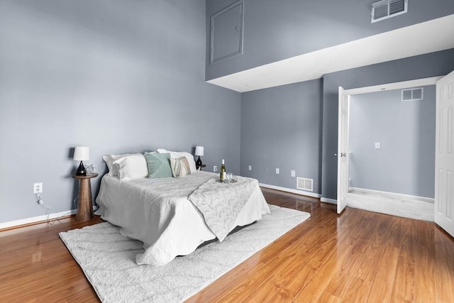 bedroom featuring a towering ceiling and hardwood / wood-style floors