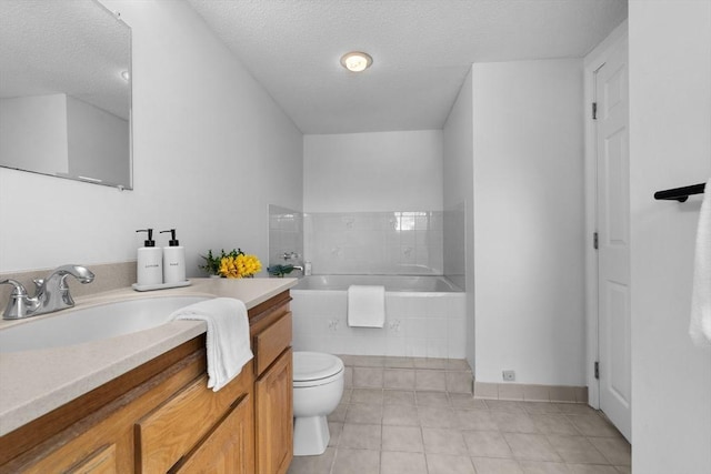 bathroom featuring vanity, a relaxing tiled tub, toilet, tile patterned floors, and a textured ceiling