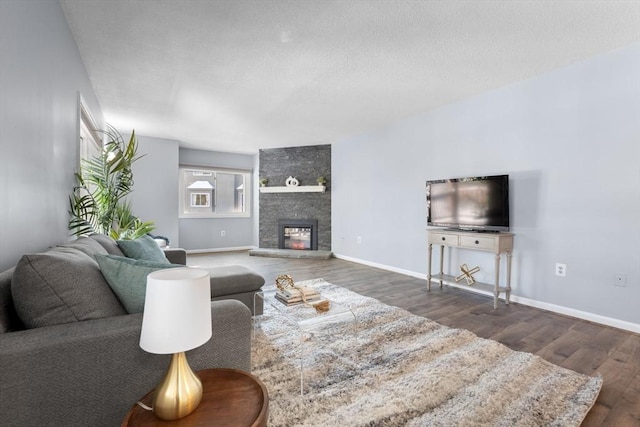 living room with dark wood-type flooring, a textured ceiling, and a fireplace