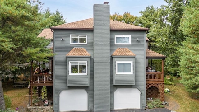 rear view of property with a garage and a deck