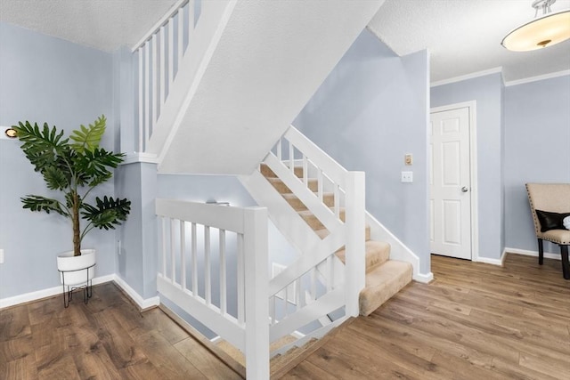 stairs with crown molding and hardwood / wood-style floors