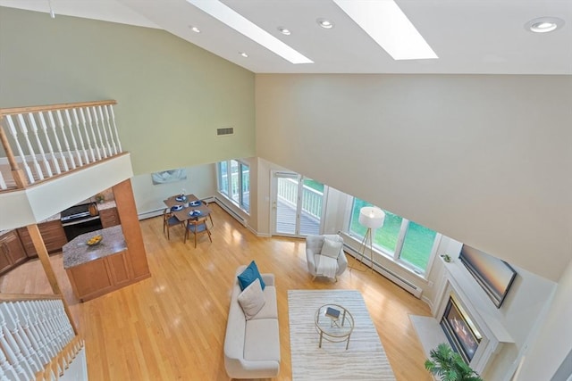 501 Lexington St Unit 35, Waltham, MA 02452 - living room featuring a fireplace with flush hearth, high vaulted ceiling, plenty of natural light, a skylight, and a baseboard radiator