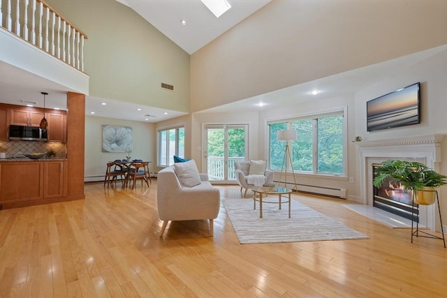 501 Lexington St Unit 35, Waltham, MA 02452 - living area featuring baseboard heating, light wood-style floors, a fireplace, high vaulted ceiling, and a skylight