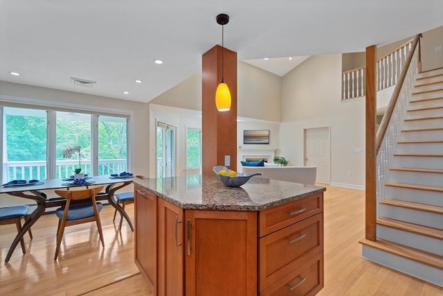 501 Lexington St Unit 35, Waltham, MA 02452 - kitchen with a fireplace, stone counters, brown cabinets, light wood-style floors, and a kitchen island