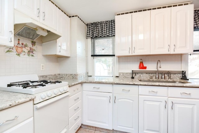 kitchen with under cabinet range hood, white gas range, white cabinets, and a sink