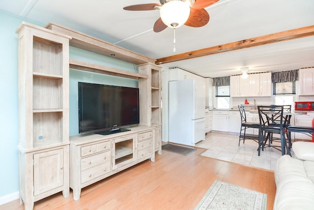 living area featuring light wood-type flooring, beam ceiling, and ceiling fan