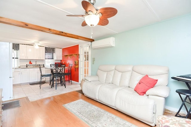 living area with ceiling fan, light wood-type flooring, beamed ceiling, and a wall mounted air conditioner