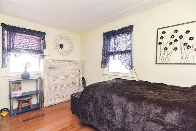 bedroom featuring ornamental molding and wood finished floors