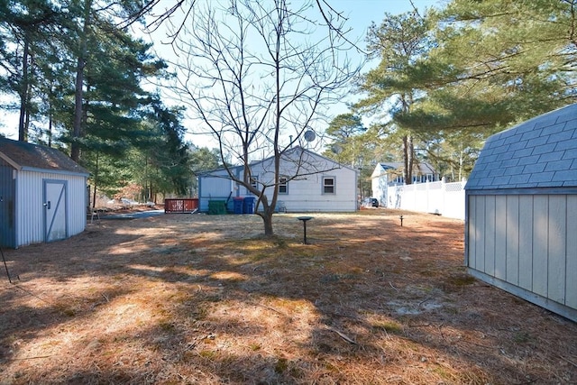 view of yard featuring a storage shed, an outdoor structure, and fence