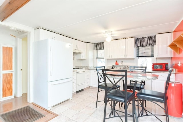 kitchen featuring light countertops, white appliances, under cabinet range hood, and white cabinets