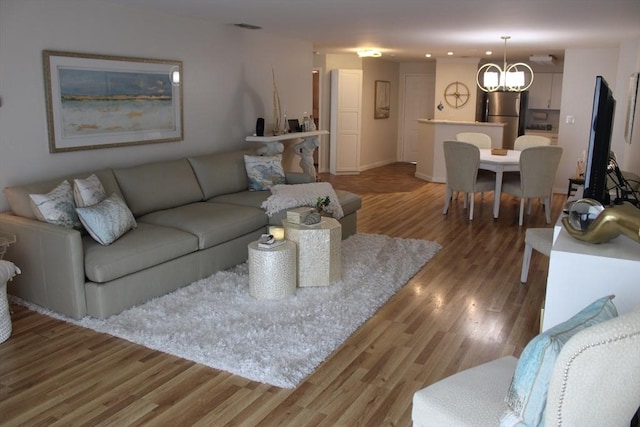 living room featuring an inviting chandelier, baseboards, recessed lighting, and wood finished floors