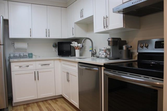 kitchen featuring appliances with stainless steel finishes, a sink, light countertops, under cabinet range hood, and white cabinetry