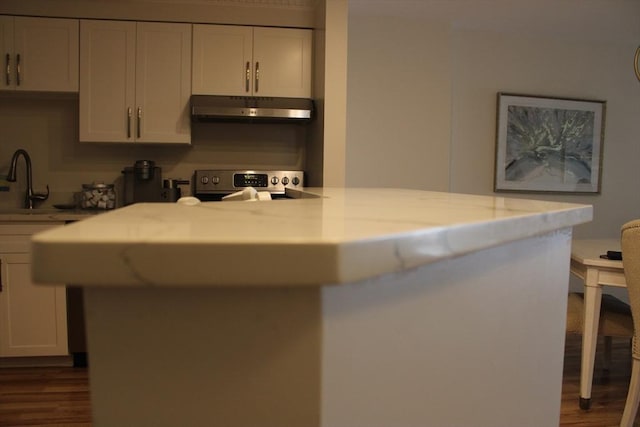 kitchen featuring under cabinet range hood, white cabinetry, range, and dark wood-type flooring