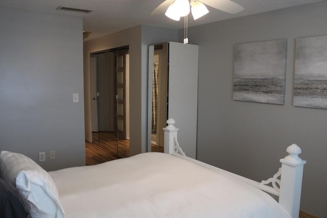 bedroom with ceiling fan, visible vents, and wood finished floors