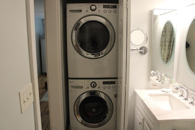 clothes washing area featuring a sink and stacked washer and dryer