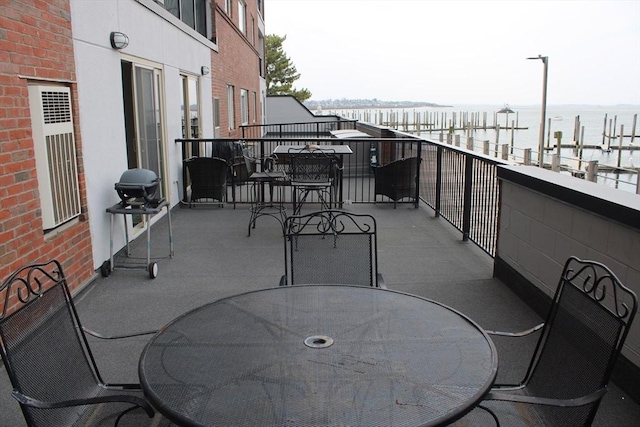 balcony featuring area for grilling, a water view, and outdoor dining space