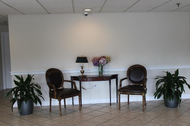living area with a drop ceiling and tile patterned flooring