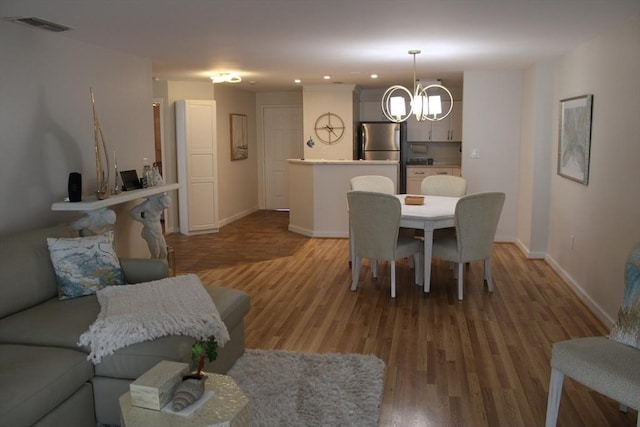 dining space with a notable chandelier, recessed lighting, baseboards, wood finished floors, and visible vents