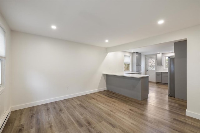 53 Kalish Ave, Enfield, CT 06082 - kitchen with a baseboard radiator, a peninsula, recessed lighting, gray cabinets, and wood finished floors