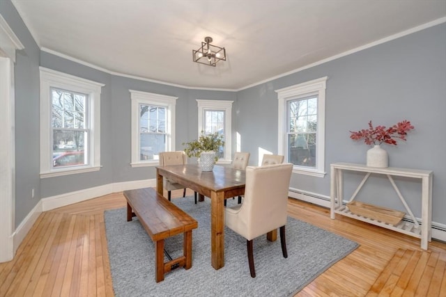 dining room with a chandelier, light wood-type flooring, baseboard heating, and ornamental molding