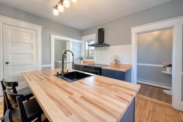 kitchen featuring sink, baseboard heating, black electric range, blue cabinets, and ventilation hood