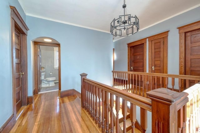 hall with ornamental molding, light hardwood / wood-style floors, and a notable chandelier