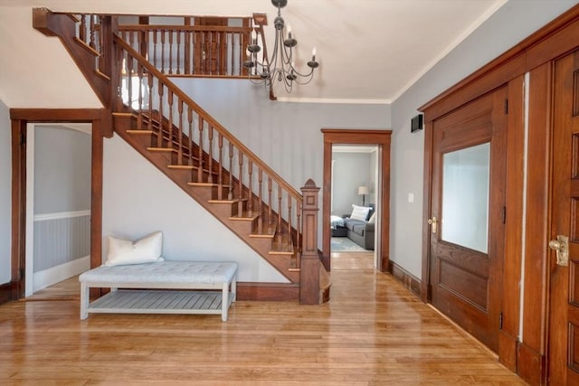 foyer entrance with a chandelier, light hardwood / wood-style flooring, and ornamental molding