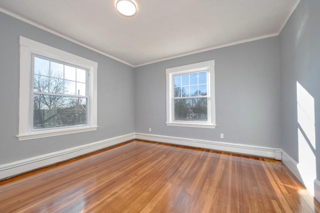 empty room with hardwood / wood-style flooring, crown molding, and a baseboard heating unit