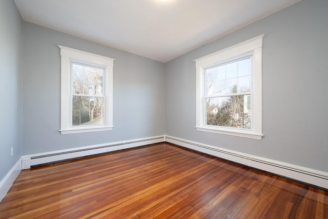 empty room with hardwood / wood-style floors and a baseboard heating unit