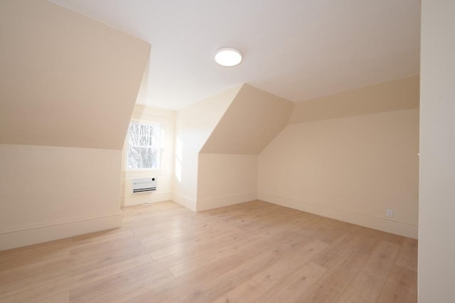 additional living space featuring a wall mounted air conditioner, light hardwood / wood-style flooring, and lofted ceiling