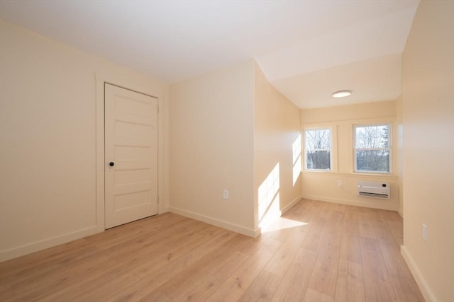 empty room with an AC wall unit and light hardwood / wood-style floors