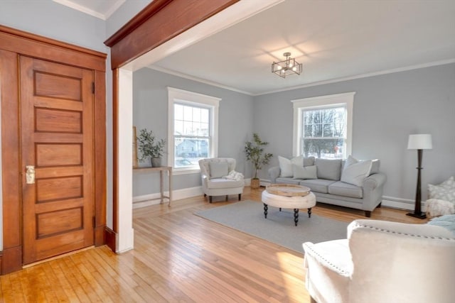 living room featuring an inviting chandelier, crown molding, light hardwood / wood-style flooring, a baseboard radiator, and plenty of natural light