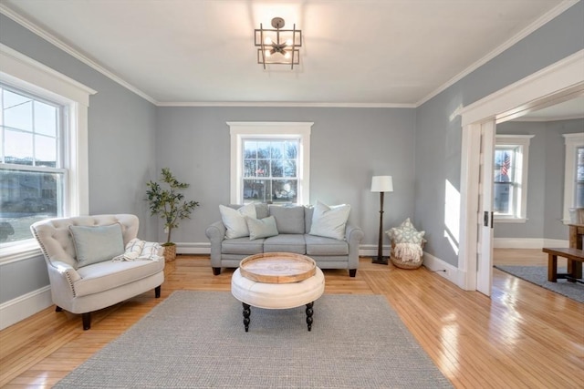 living room with a wealth of natural light, light hardwood / wood-style flooring, ornamental molding, and a baseboard heating unit