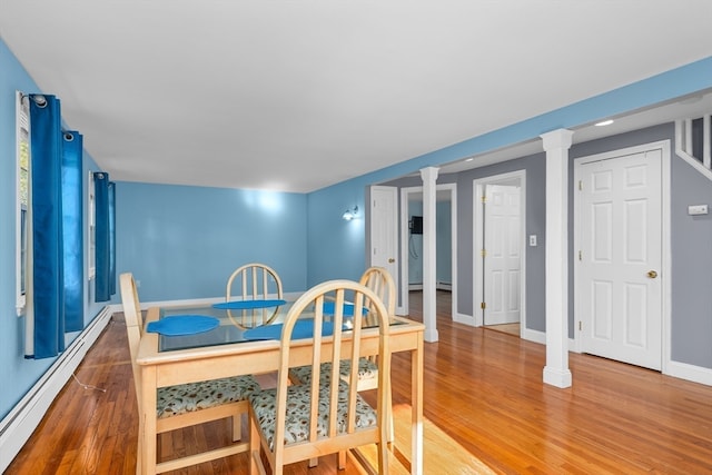 dining area with wood-type flooring, a baseboard heating unit, and decorative columns