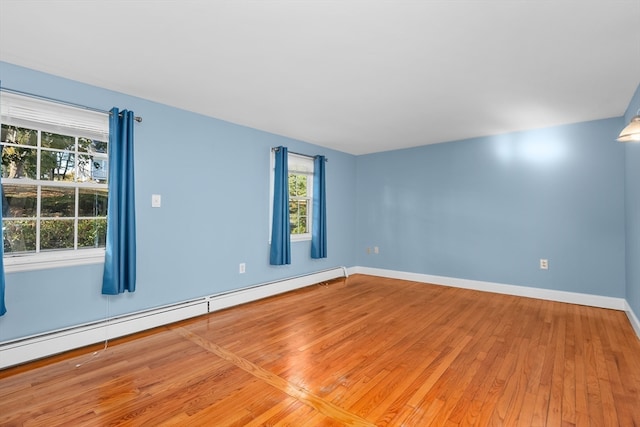 spare room featuring a baseboard heating unit and wood-type flooring