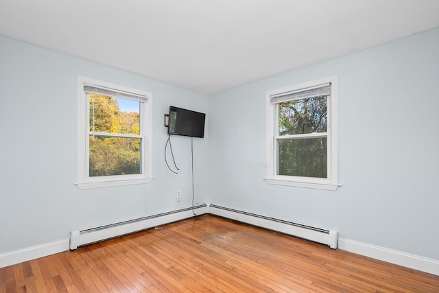 spare room featuring baseboard heating, plenty of natural light, and light hardwood / wood-style floors