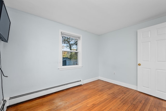 empty room with a baseboard radiator and light hardwood / wood-style flooring