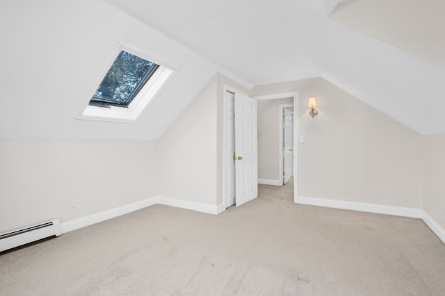 additional living space featuring vaulted ceiling with skylight, light colored carpet, and a baseboard radiator