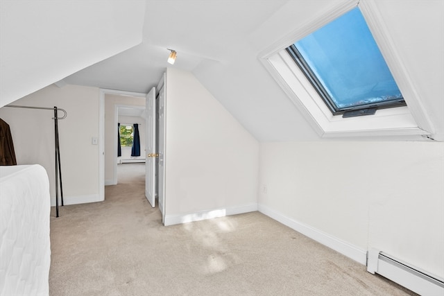 additional living space featuring lofted ceiling with skylight, light carpet, and a baseboard heating unit