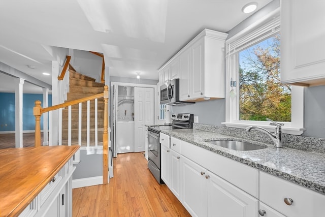 kitchen featuring light stone counters, stainless steel appliances, light wood-type flooring, white cabinetry, and sink