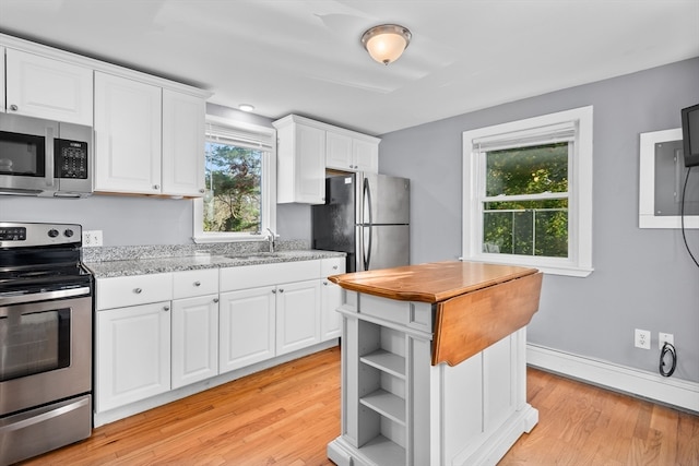 kitchen with light wood-type flooring, white cabinetry, light stone counters, and stainless steel appliances