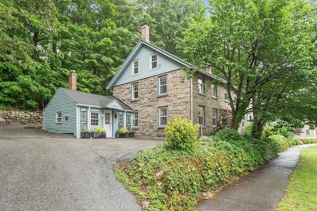 18 River St Unit 18, Andover, MA 01810 - traditional-style home featuring stone siding, a chimney, and driveway
