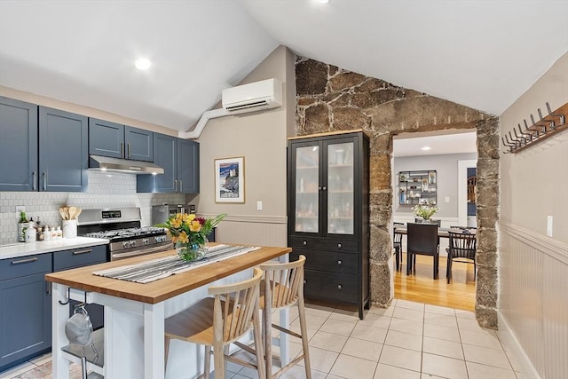 18 River St Unit 18, Andover, MA 01810 - kitchen with gas range, under cabinet range hood, a wall mounted AC, wainscoting, and vaulted ceiling