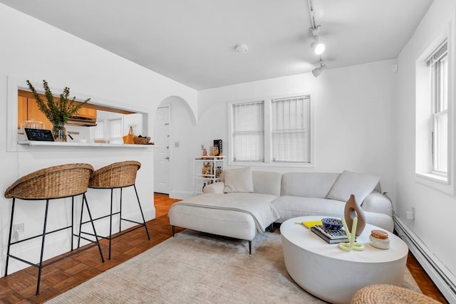 living room with rail lighting, a baseboard heating unit, light parquet flooring, and plenty of natural light