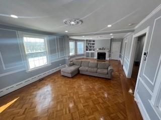 living room with crown molding, a baseboard radiator, and dark parquet floors