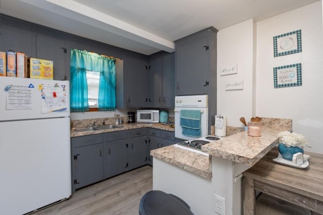 76 Blackstone River Rd, Worcester, MA 01607 - kitchen featuring white appliances, a peninsula, light wood-style flooring, light countertops, and a breakfast bar area