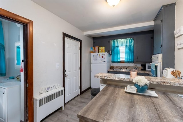 76 Blackstone River Rd, Worcester, MA 01607 - kitchen featuring white appliances, radiator heating unit, light wood finished floors, light countertops, and a sink