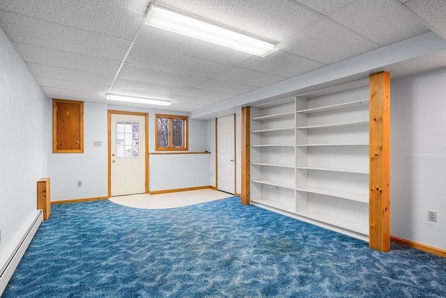 basement featuring baseboard heating, a paneled ceiling, and dark colored carpet