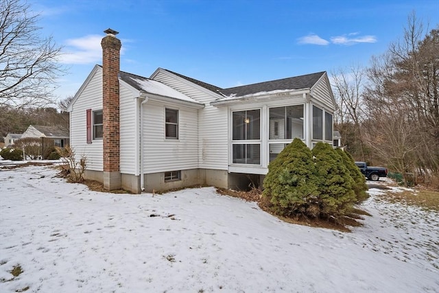 snow covered property featuring a sunroom